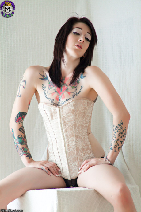 Tattooed Goth Angel Beau removes a corset to pose undressed in black socks