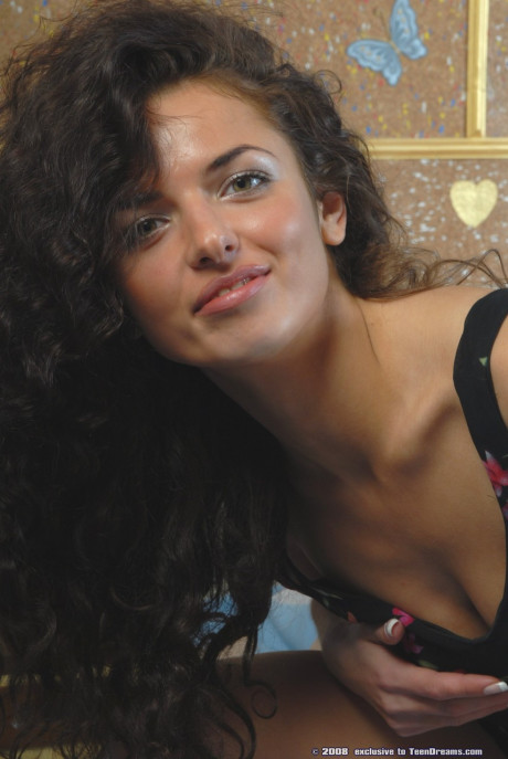 Curly haired young Mia undresses and exposes her sexy body with tan lines