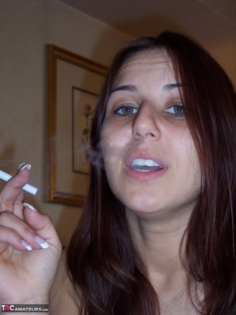 Totally undressed chick girlfriend woman Lexxxi sits on her bed while smoking a cigarette