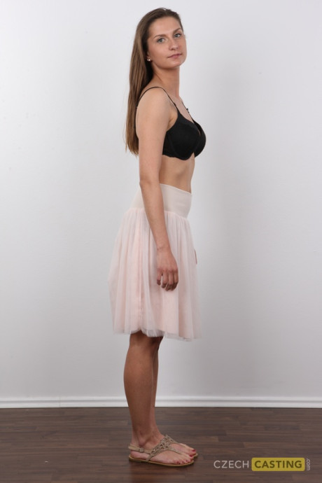 Caucasian amateur takes off her clothes while standing in front of a wall