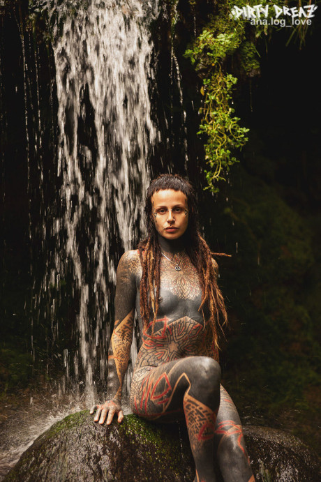 Heavily tattooed lesbians hold each other while totally nude on a bridge