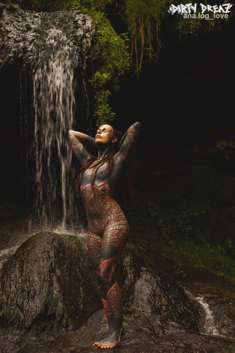 Heavily tattooed lesbians hold each other while totally nude on a bridge