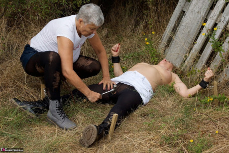Mature British girl restrains busty old lady woman Speedy Bee while in the outdoors