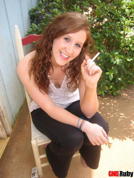 Young young ginger head flashes a boob while having a cigarette on a back porch