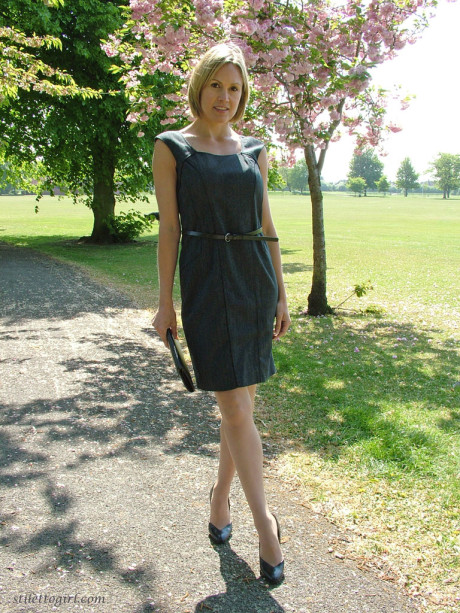 Clothed business girl shows off her pretty legs in high heels in the park