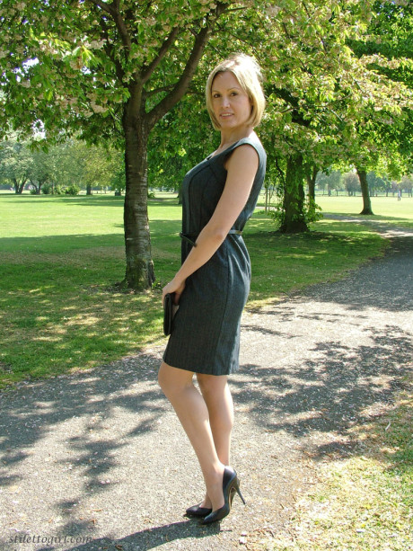Clothed business girl shows off her pretty legs in high heels in the park
