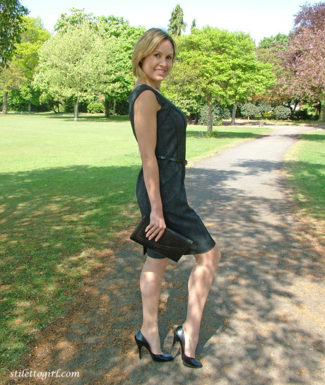 Clothed business girl shows off her pretty legs in high heels in the park