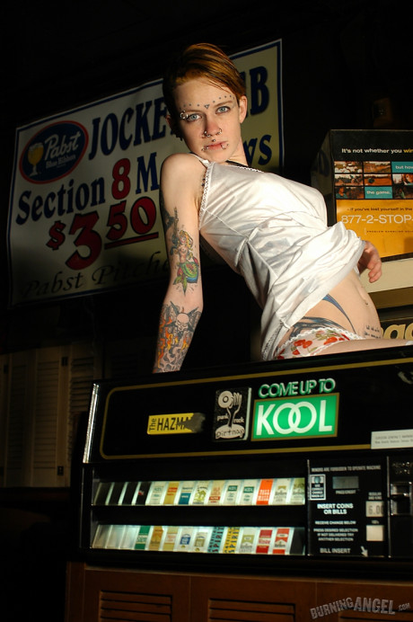 Babe with short hair and heavy tattoos is a striptease at an empty bar