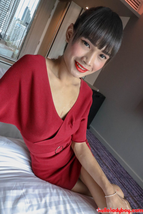 Brunette oriental transexual Mei removes her red dress and poses in underwear