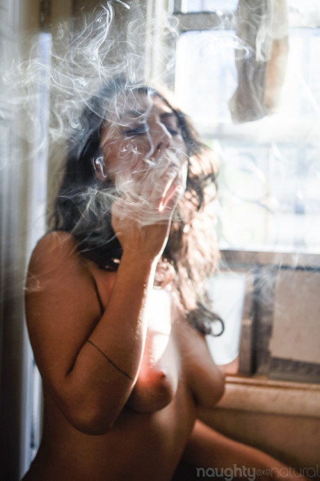 Amateur babe Nikki Silver smokes a spliff while posing undressed indoors and out