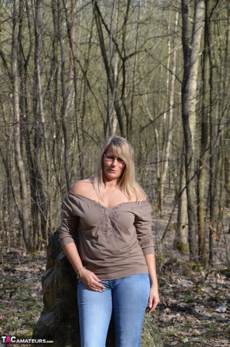 Middle-aged yellow-haired lovely Susi pulls down her jeans to show her bare behind