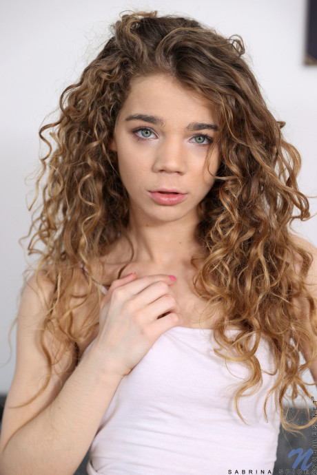 Curly haired teenie Sabrina Spice displays her wide pierced vagina and charming feet