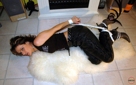 Clothed Caucasian female Jenna struggles on a rug while hogtied