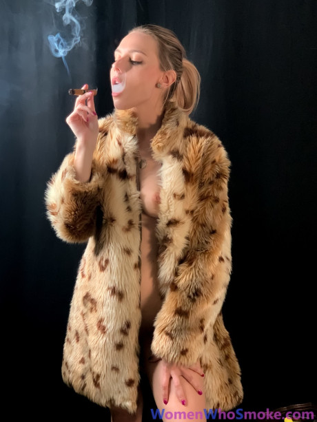 Blondy with a ponytail poses in her fur coat as she smokes a cigarette