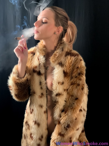 Blondy with a ponytail poses in her fur coat as she smokes a cigarette