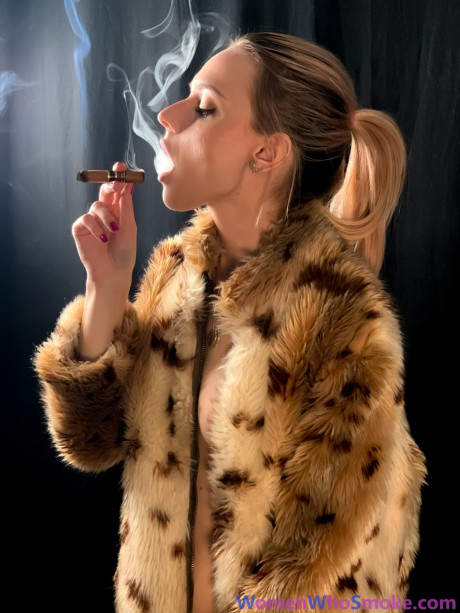 Blondy with a ponytail poses in her fur coat as she smokes a cigarette