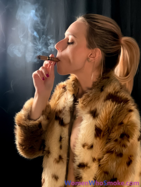 Blondy with a ponytail poses in her fur coat as she smokes a cigarette