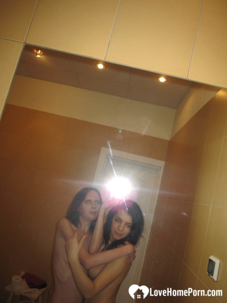 Amateur lesbians fondle each other's small breasts while posing in the mirror