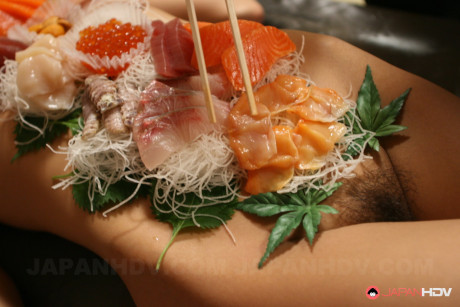 Attractive oriental babe Ramu Nagatsuki gets toyed while covered with sushi on a table