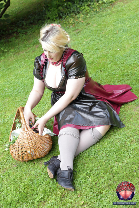 Overweight yellow-haired Darkwing Zero models on a lawn in a rubber dress