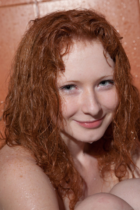 Curly-haired young Rochelle A presents her nice titties and trimmed redhead snatch
