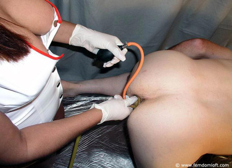 Kinky nurse gives a nude male an enema after inserting a butt plug