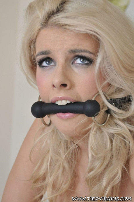 Ravishing blondy sports a horse bit while showing her great breasts in a box