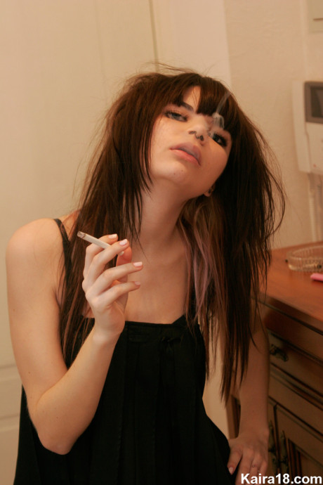 Petite teenie Kaira 18 smokes a cigarette while getting undressed in her bedroom