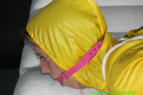 Caucasian girl woman Pia is ball gagged and hogtied in a yellow rain suit