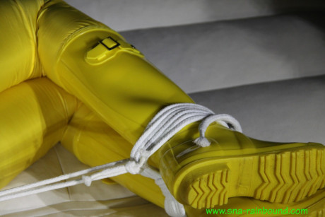 Caucasian girl woman Pia is ball gagged and hogtied in a yellow rain suit