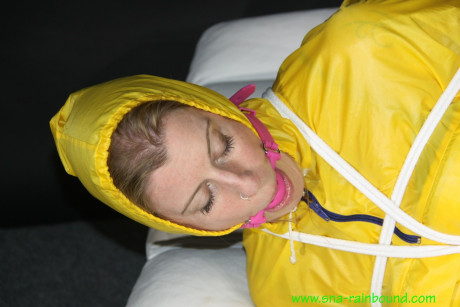 Caucasian girl woman Pia is ball gagged and hogtied in a yellow rain suit