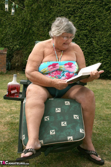 Slutty amateur old lady Libby inserting a bottle in her chunky cunt in the garden