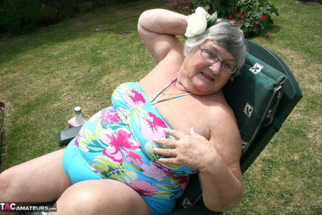 Slutty amateur old lady Libby inserting a bottle in her chunky cunt in the garden