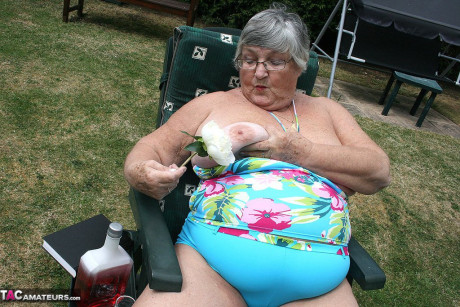 Slutty amateur old lady Libby inserting a bottle in her chunky cunt in the garden