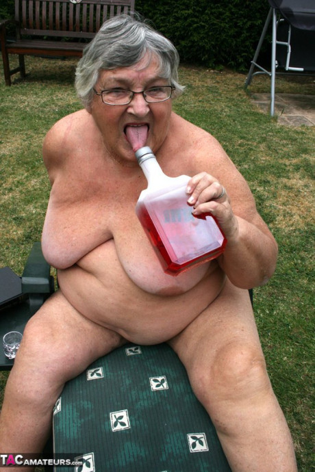 Slutty amateur old lady Libby inserting a bottle in her chunky cunt in the garden