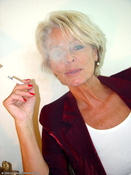 Mature skank woman Justine exposes her saggy tanned melons while smoking a cigarette