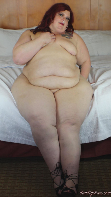 Redhead SSBBW Nikki Cakes shows her monstrous behind while face down on a bed