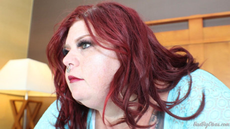 Redhead SSBBW Nikki Cakes shows her monstrous behind while face down on a bed