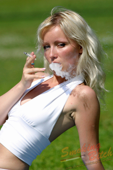 Hot blonde smokes a cigarette during upskirt action on a public bench