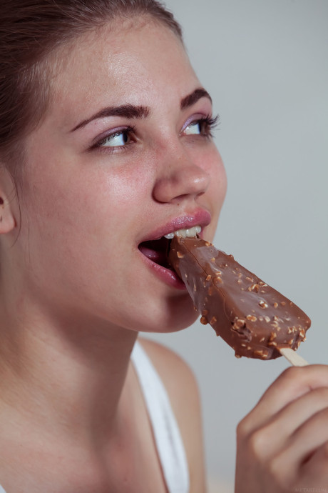 Fine teenie Jasmina eats an ice-cream and strips to pose on a bed