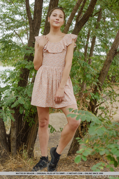 Petite young Mattie strips totally nude in front of a tree while outdoors