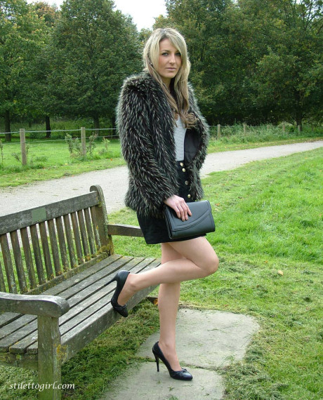 Leg model poses on a country bench in ebony skirt and pumps