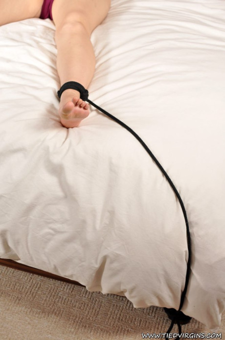 Topless blondie is tied to a double bed at her wrist and ankles with ropes