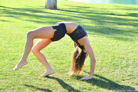 Teenage beauty in charming outfit Zoe doing exercise outdoors by the water