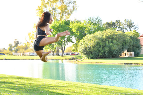 Teenage beauty in charming outfit Zoe doing exercise outdoors by the water