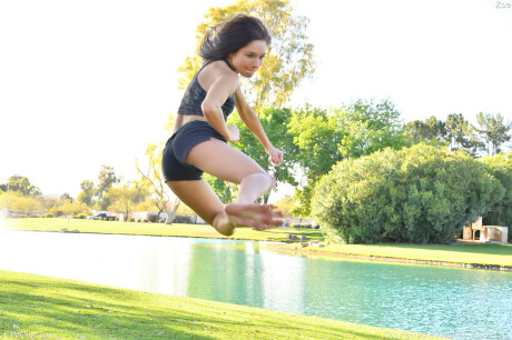 Teenage beauty in charming outfit Zoe doing exercise outdoors by the water