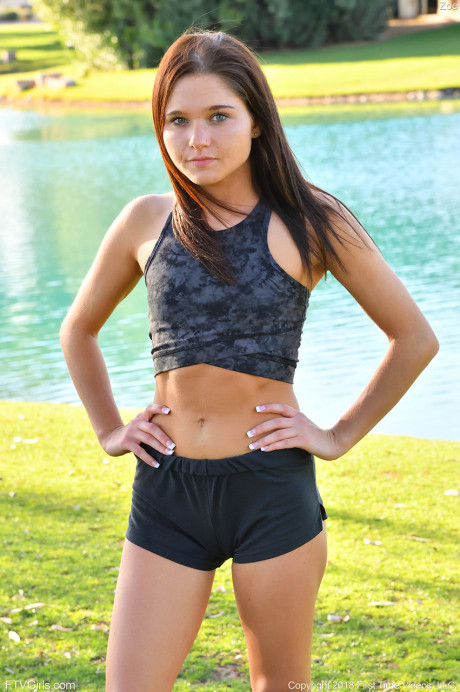 Teenage beauty in charming outfit Zoe doing exercise outdoors by the water