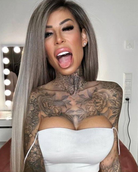 Tattooed amateur babe poses in pink fishnets & flaunts her hot legs & cleavage