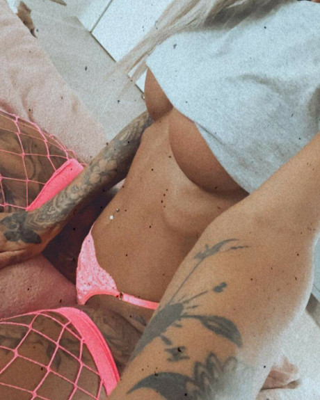 Tattooed amateur babe poses in pink fishnets & flaunts her hot legs & cleavage