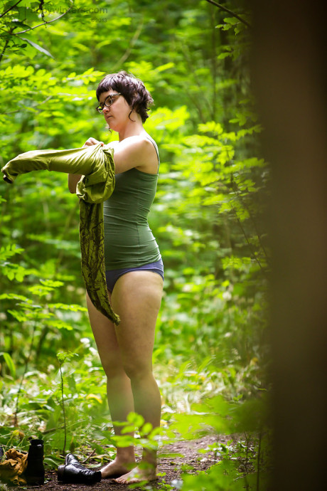 Voyeur snaps of nude brunette lady chick in glasses getting dressed in woods